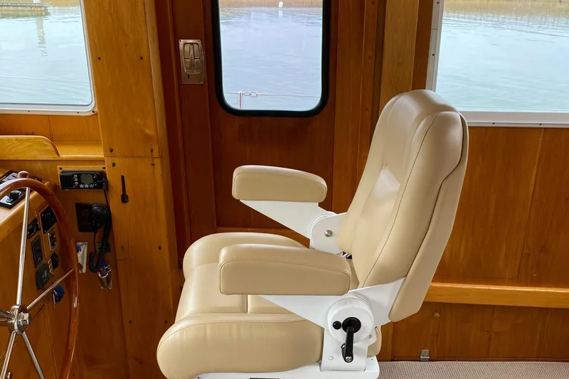 Slide: The Image of Captain's chair in 1987 Jarvis Newman 46' Flybridge Cruiser, featuring wooden interior and helm. - 20