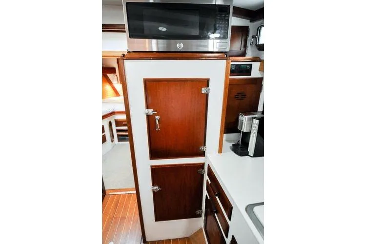 Slide: The Image of 1987 Jarvis Newman 46' Flybridge Cruiser galley with microwave, wooden cabinets, and coffee maker. - 33