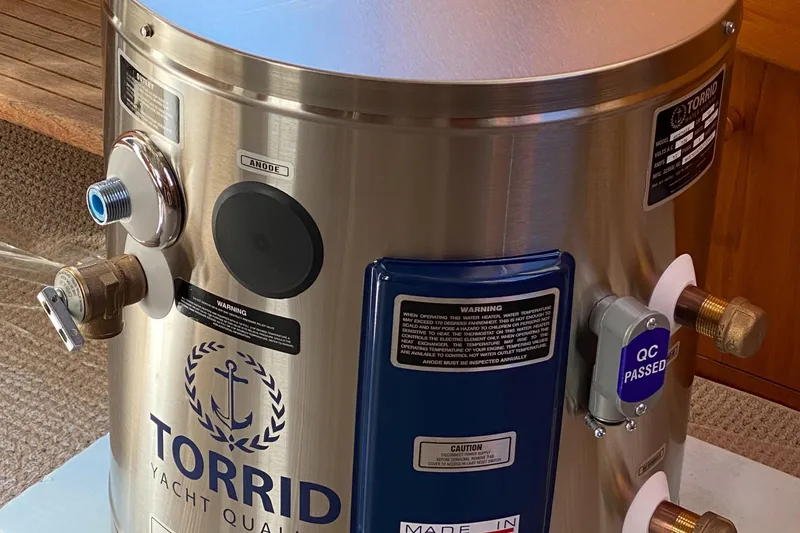 Slide: The Image of Stainless steel Torrid yacht water heater with various fittings and labels, onboard a 1987 Jarvis Newman cruiser. - 87