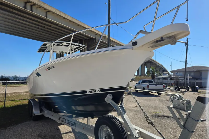 Slide: The Image of 1989 Blackfin 272 CC boat on trailer under bridge, clear sky background. - 2