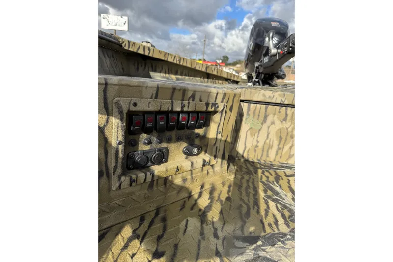 Slide: The Image of 2026 SeaArk 1752 Slayer X Pro boat dashboard with switches and camouflage design. - 8