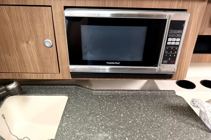 Slide: The Image of 2014 Boston Whaler 285 Conquest kitchen with microwave and sink. - 18