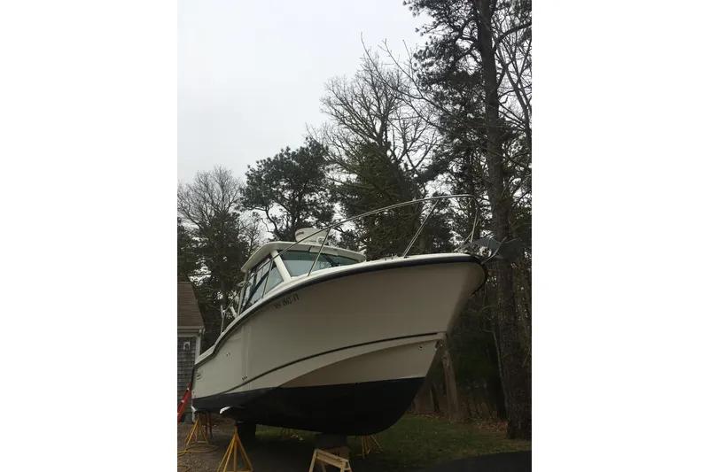 Slide: The Image of 2014 Boston Whaler 285 Conquest boat on stands, surrounded by trees. - 2
