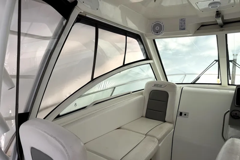 Slide: The Image of Interior of 2014 Boston Whaler 285 Conquest boat, featuring cushioned seating and windows. - 8