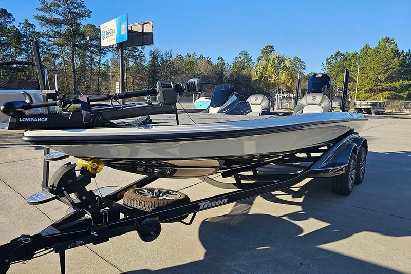 Slide: The Image of 2026 Triton 20XP Patriot boat on trailer, parked outdoors with trees in background. - 5