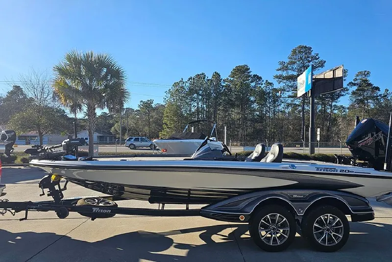 Slide: The Image of 2026 Triton 20XP Patriot boat on trailer, parked outdoors under clear sky. - 6