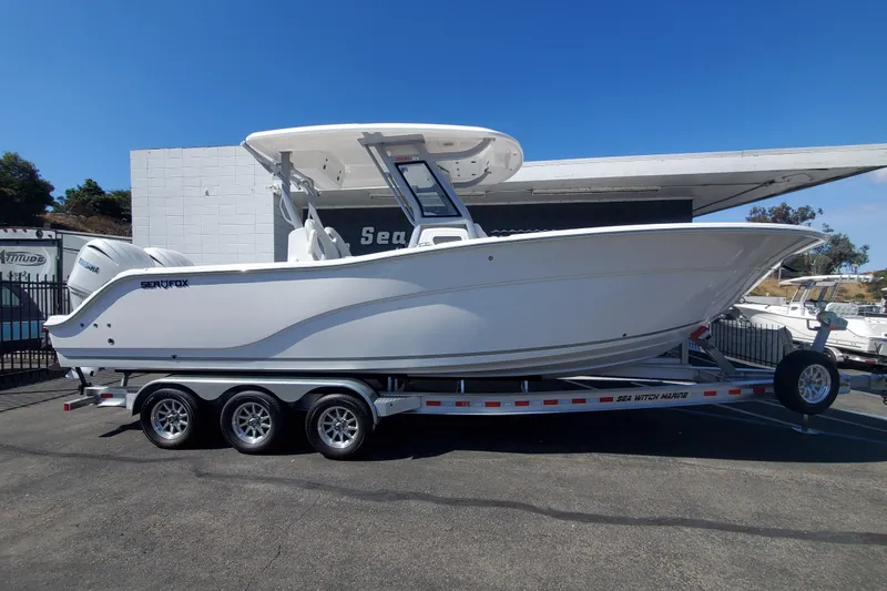 The Image of 2026 Sea Fox 288 Commander boat on trailer, parked outdoors under clear blue sky. - 0