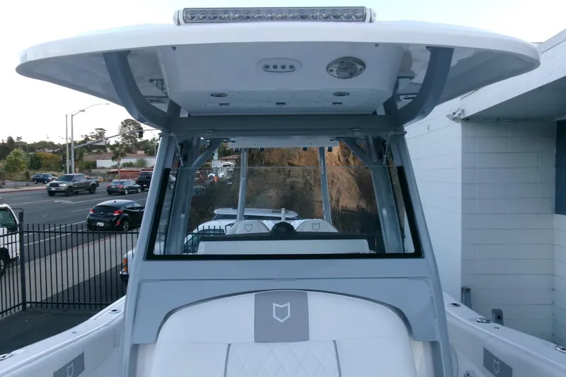 Slide: The Image of 2026 Sea Fox 288 Commander boat with T-top and windshield, parked near a road. - 16
