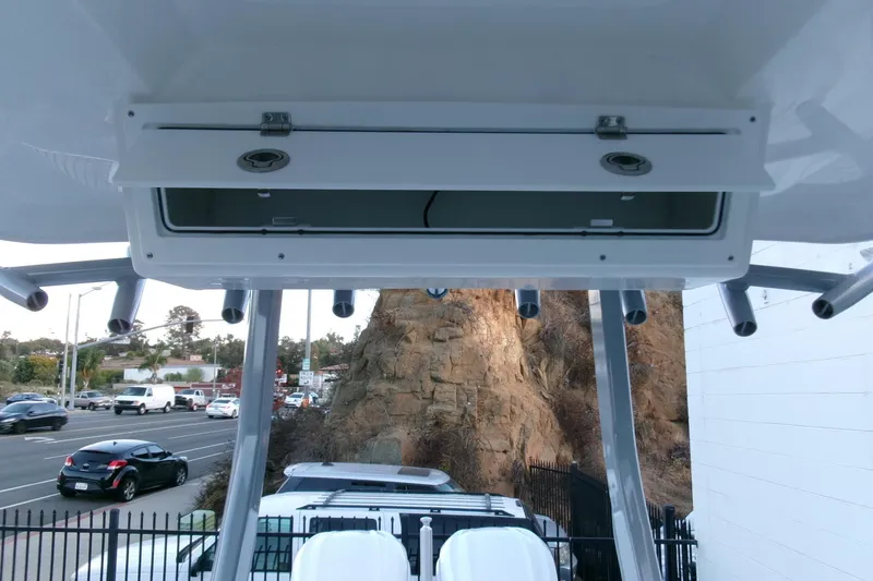 Slide: The Image of 2026 Sea Fox 288 Commander boat storage compartment with rod holders, parked near a busy road. - 24