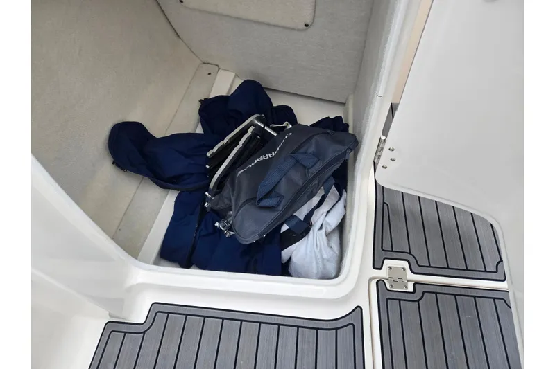 Slide: The Image of Storage compartment in 2016 Chaparral Vortex 243 VRX boat with bags and clothing. - 15