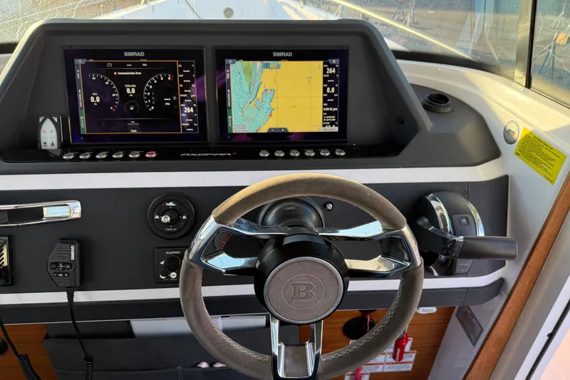 Slide: The Image of 2021 Axopar 28 Cabin dashboard with dual Simrad displays and steering wheel. - 11