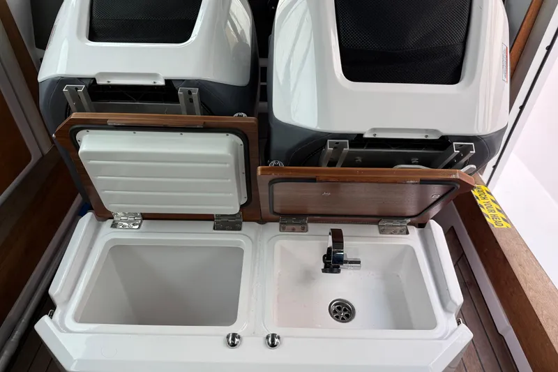 Slide: The Image of 2021 Axopar 28 Cabin interior with open storage compartments and sink. - 25