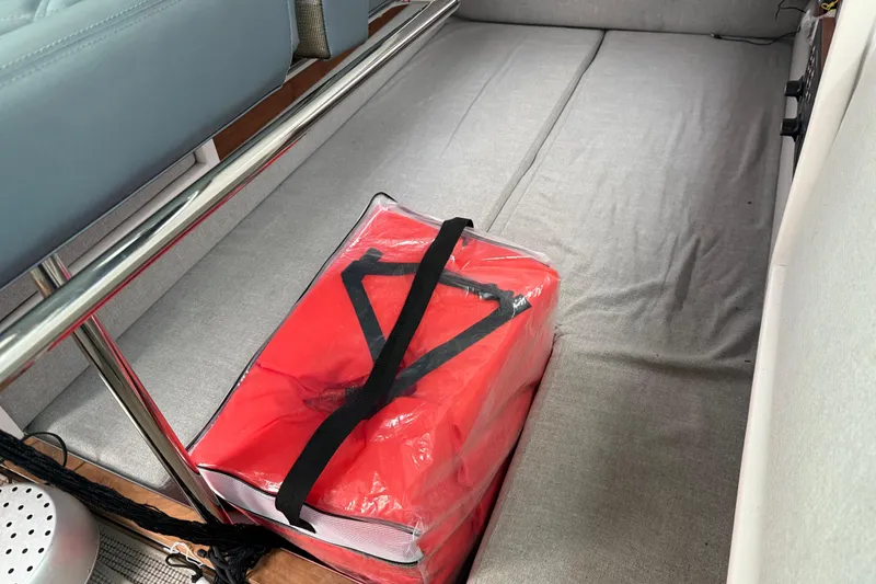 Slide: The Image of Interior of 2021 Axopar 28 Cabin with red storage bag on gray flooring. - 28