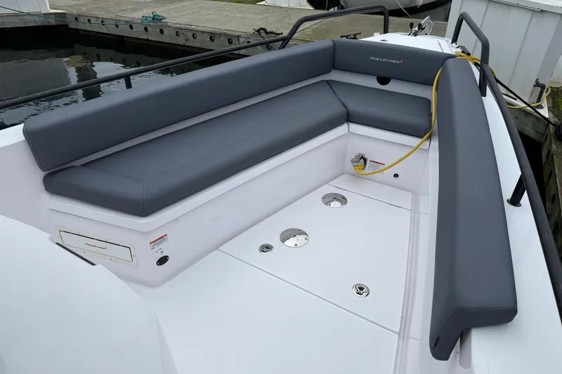 Slide: The Image of 2021 Axopar 28 Cabin boat interior with gray seating and dockside view. - 33