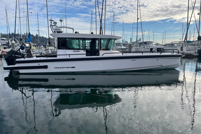 Slide: The Image of 2021 Axopar 28 Cabin boat docked in a marina with reflections on water. - 45