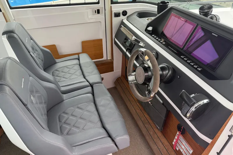 Slide: The Image of Interior of 2021 Axopar 28 Cabin boat with dual seats and modern dashboard. - 9