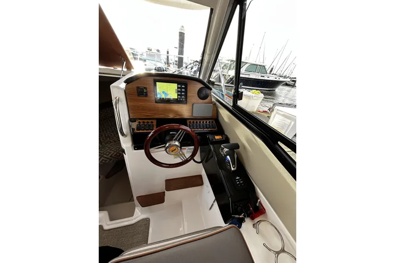 Slide: The Image of 2024 Cutwater 248 boat helm with navigation display and steering wheel, docked at marina. - 14