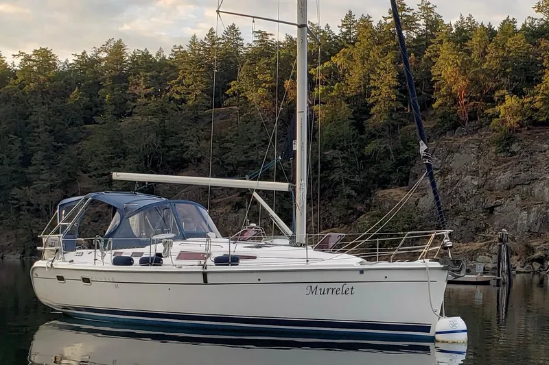 The Image of Sailboat "Murrelet" on calm water, Hunter 38 model, 2009, with forested backdrop. - 0