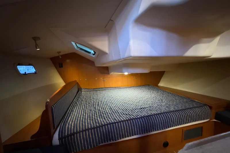 Slide: The Image of 2009 Hunter 38 yacht interior cabin with striped bedding and wooden accents. - 10