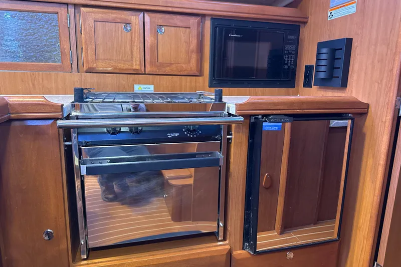 Slide: The Image of 2009 Hunter 38 yacht kitchen with wooden cabinets, stove, microwave, and mini-fridge. - 8