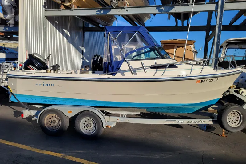Slide: The Image of 1998 Arima Sea Ranger 19 boat on trailer, parked outdoors, with Suzuki outboard motor. - 1