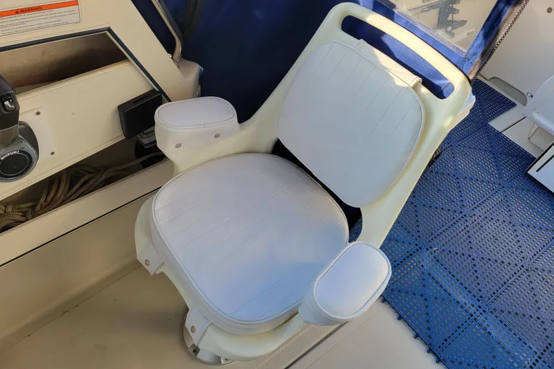 Slide: The Image of White captain's chair on 1998 Arima Sea Ranger 19 boat, featuring blue accents and control panel. - 11