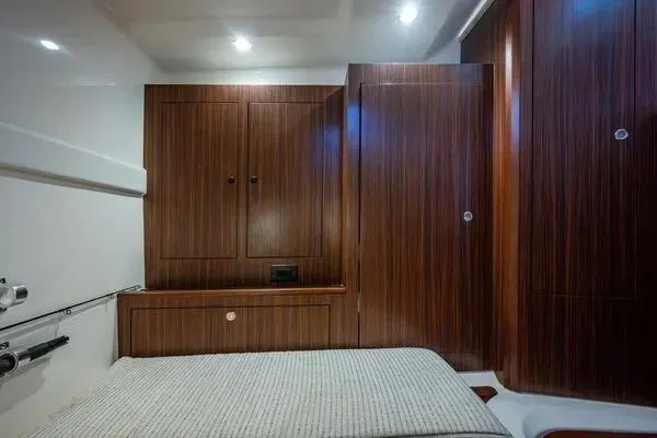 Slide: The Image of 2023 Pursuit OS 355 Offshore cabin with wood paneling and cozy bed. - 15