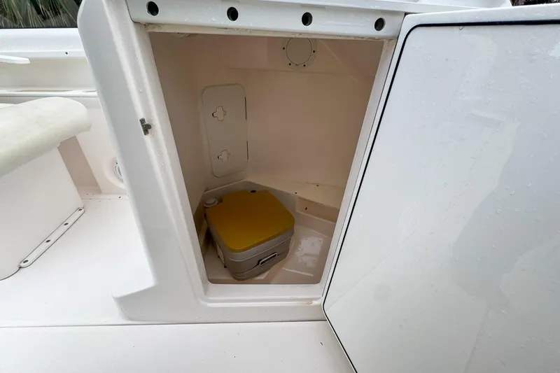 Slide: The Image of 2014 Everglades 230 Dual Console boat storage compartment with portable toilet. - 111