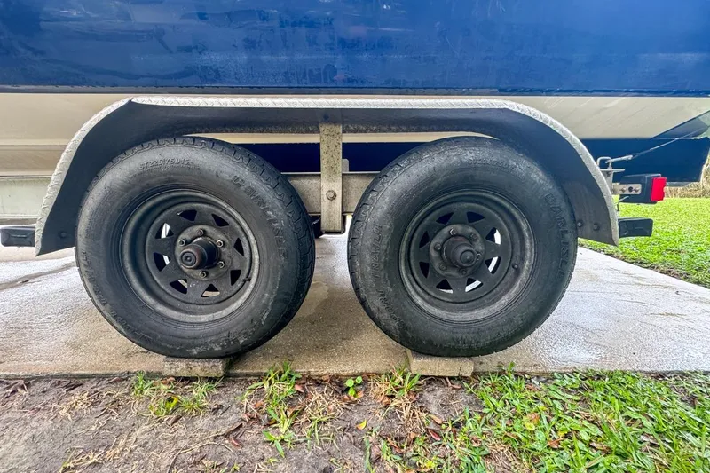 Slide: The Image of Trailer wheels of a 2014 Everglades 230 Dual Console boat on concrete. - 116