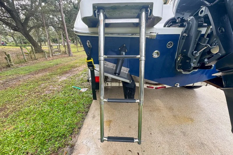 Slide: The Image of 2014 Everglades 230 Dual Console boat with rear ladder on a grassy driveway. - 18