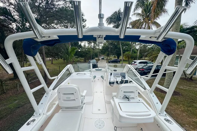 Slide: The Image of 2014 Everglades 230 Dual Console boat with seating and steering wheel, parked outdoors. - 29