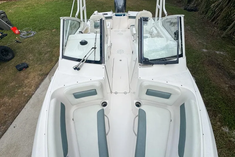 Slide: The Image of 2014 Everglades 230 Dual Console boat with open seating and windshield, parked on grass. - 55