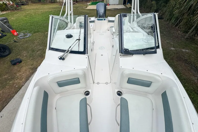 Slide: The Image of 2014 Everglades 230 Dual Console boat with open seating and windshield, parked on grass. - 56
