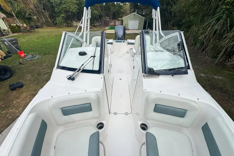 Slide: The Image of 2014 Everglades 230 Dual Console boat with spacious seating and windshield, parked outdoors. - 57