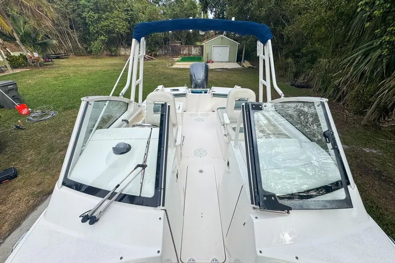 Slide: The Image of 2014 Everglades 230 Dual Console boat with blue canopy, parked on grass. - 58