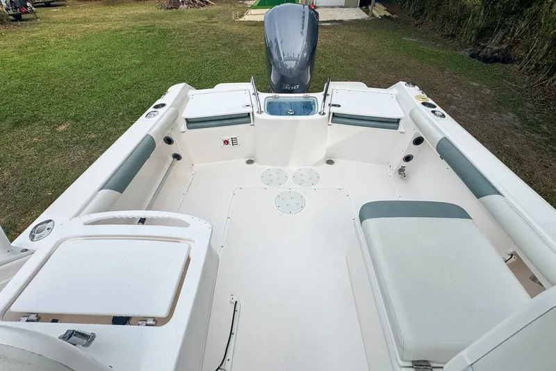 Slide: The Image of 2014 Everglades 230 Dual Console boat interior with seating and motor, parked on grass. - 64