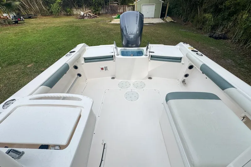 Slide: The Image of 2014 Everglades 230 Dual Console boat interior with seating and motor in a grassy yard. - 65