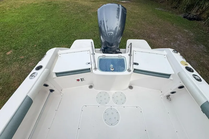 Slide: The Image of 2014 Everglades 230 Dual Console boat interior with motor, white deck, and storage compartments. - 67