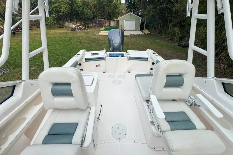 Slide: The Image of 2014 Everglades 230 Dual Console boat interior with seating and motor, parked on grass. - 68