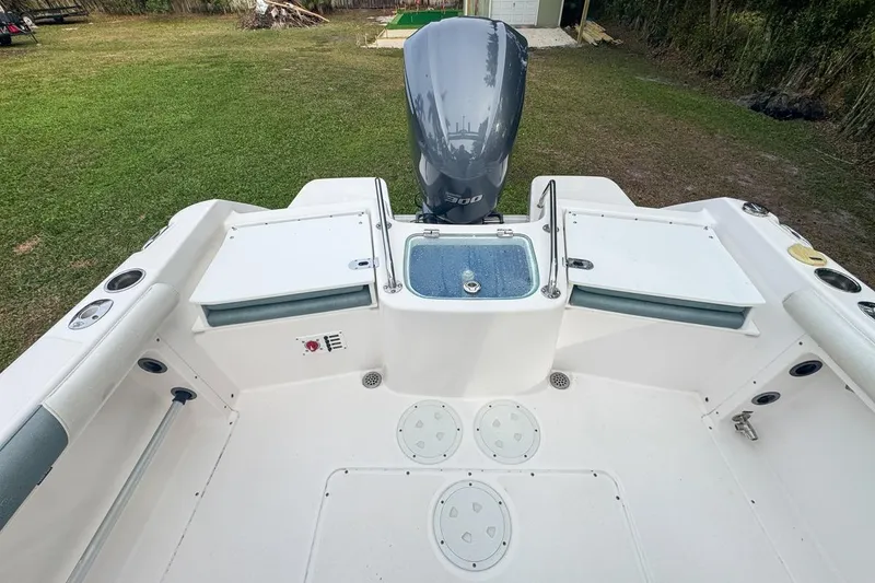 Slide: The Image of 2014 Everglades 230 Dual Console boat interior with motor, white seating, and storage compartments. - 69