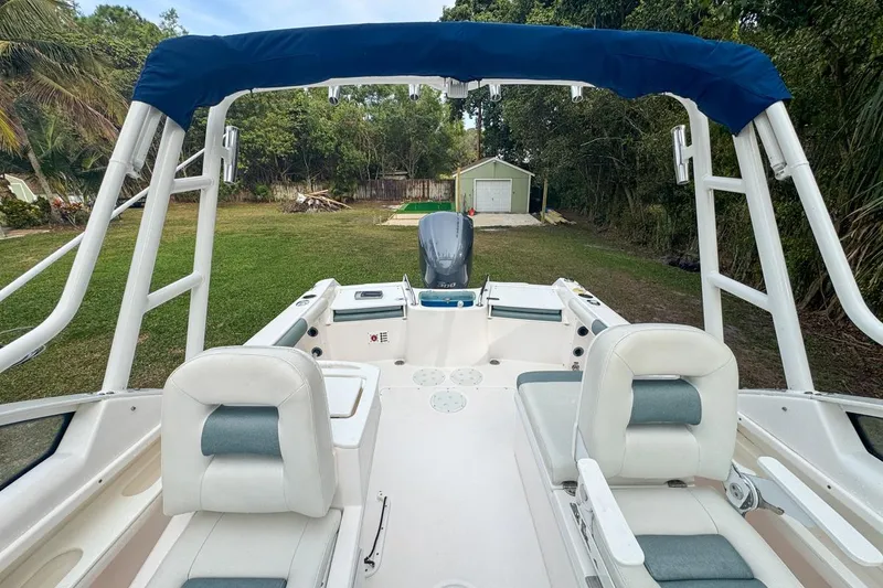 Slide: The Image of 2014 Everglades 230 Dual Console boat with blue canopy, parked on grass. - 70