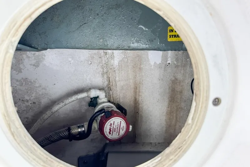 Slide: The Image of Inspection hatch of 2014 Everglades 230 Dual Console boat showing plumbing components. - 84