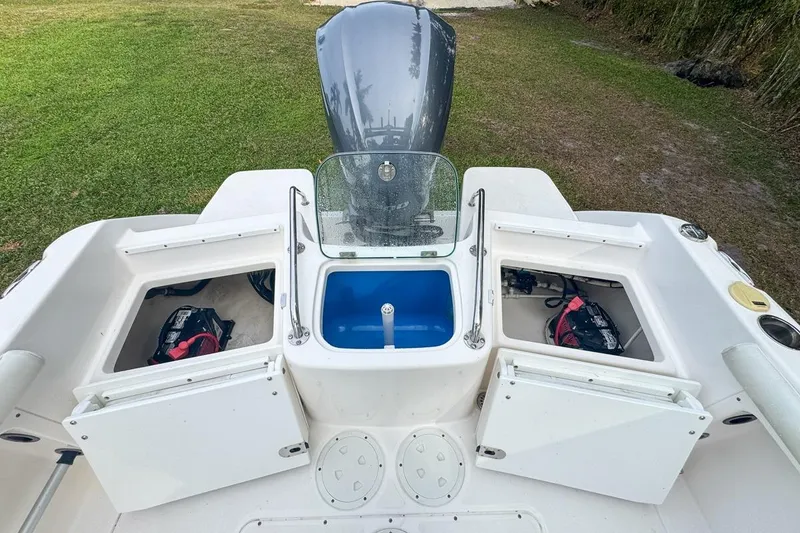Slide: The Image of 2014 Everglades 230 Dual Console boat with open storage compartments and outboard motor. - 86