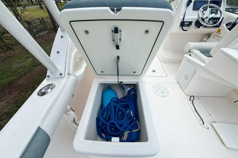 Slide: The Image of 2014 Everglades 230 Dual Console boat storage compartment with blue rope and fender. - 99
