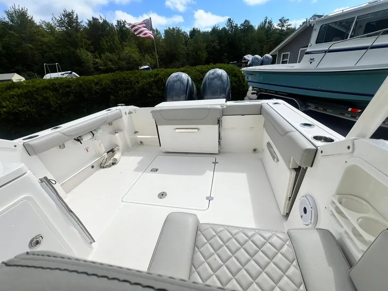 Slide: The Image of 2022 Pursuit DC 266 Dual Console boat interior with seating and storage, docked outdoors. - 10
