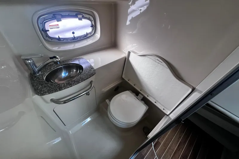 Slide: The Image of 2011 Chaparral 310 Signature boat bathroom with sink, toilet, and porthole window. - 25