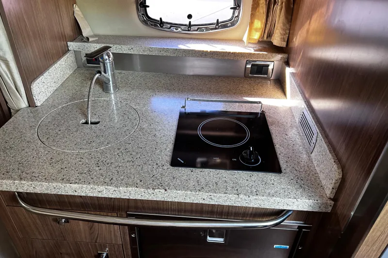 Slide: The Image of 2011 Chaparral 310 Signature boat kitchen with sink and electric stove. - 26