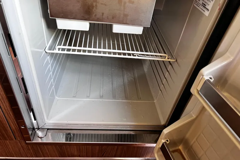 Slide: The Image of Open refrigerator inside a 2011 Chaparral 310 Signature boat, showing empty shelves. - 27