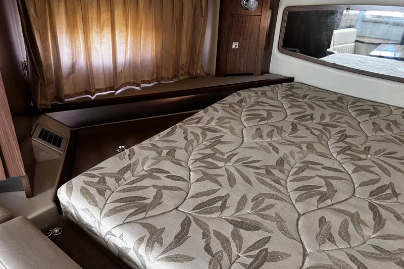 Slide: The Image of 2011 Chaparral 310 Signature cabin with patterned bedding and wooden accents. - 28