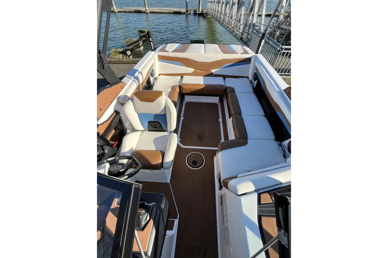 Slide: The Image of 2024 Axis T220 boat interior with brown and white seating, docked by the water. - 12